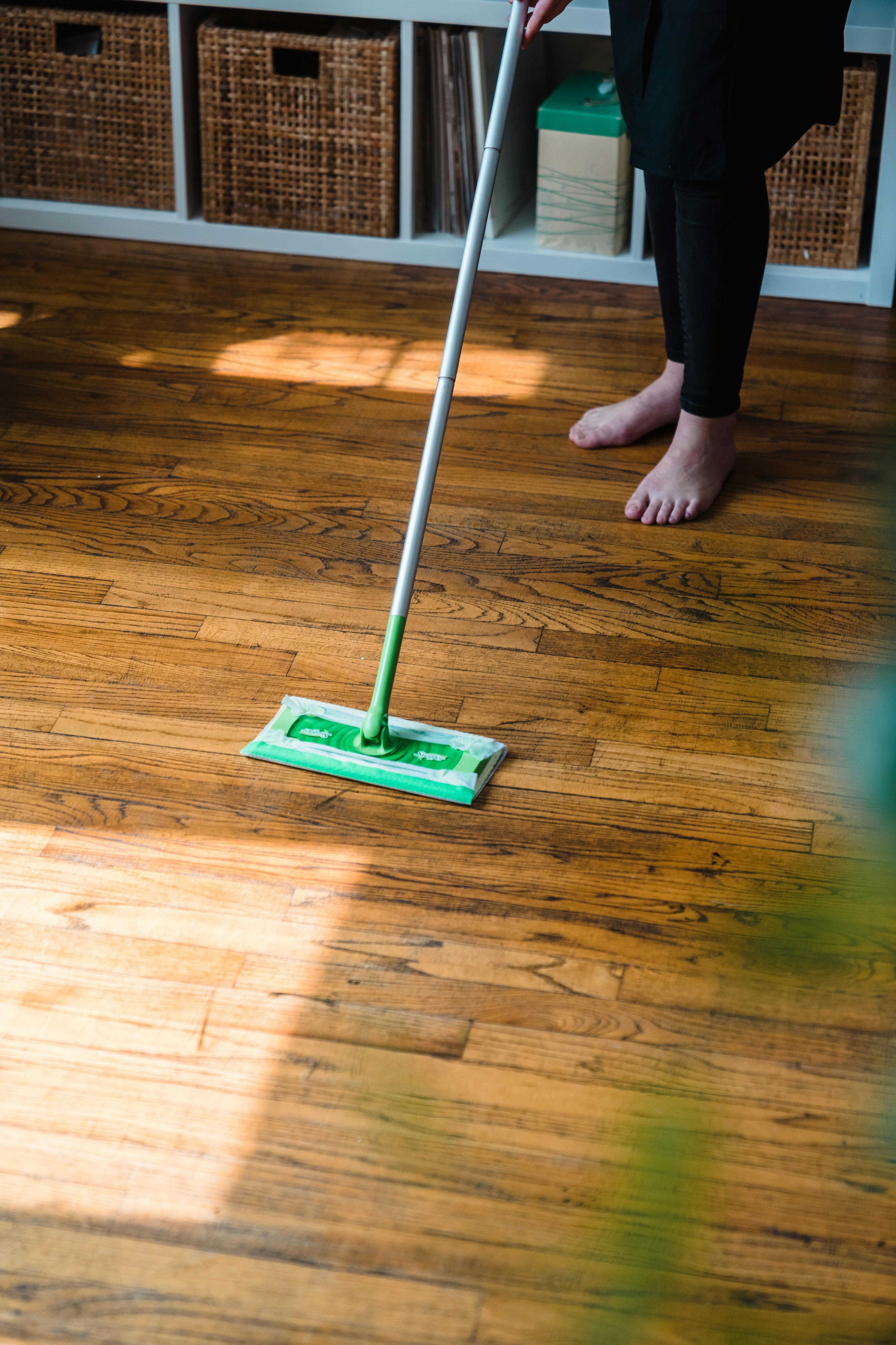 Una mopa verde sobre un piso de madera junto a una persona