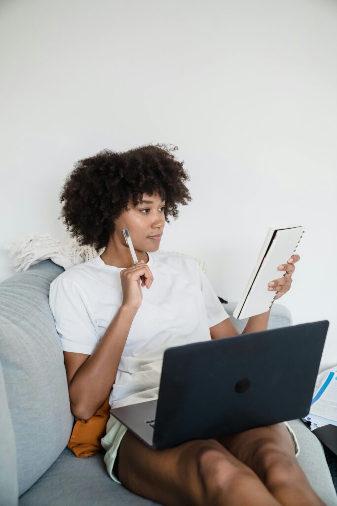 Persona con una libreta y una computadora portátil en un sofá